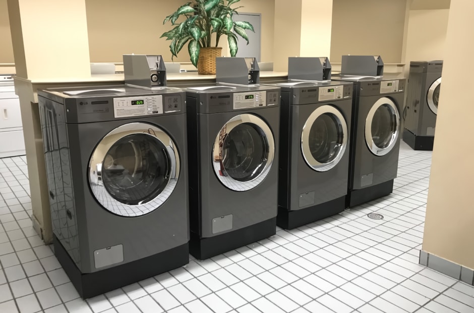 Apartment laundry room featuring LG commercial laundry front-load washing machines, neatly lined up on a clean, tiled floor.