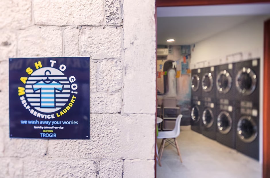 Multi-housing laundromat featuring LG commercial laundry machines, with a colorful interior and self-service signage visible at the entrance.