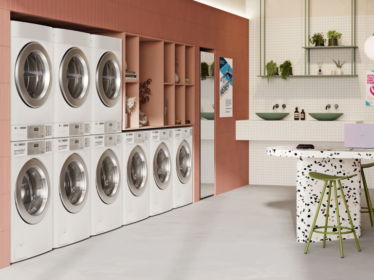 LG Commercial Laundry features eight white stackable washer-dryer units in a dormitory laundry room, neatly arranged in a modern, organized space.