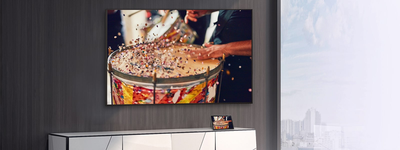 In the room, a wall-mounted TV is set up, with a tablet placed on the shelf. The tablet’s content is mirrored and displayed on the TV.