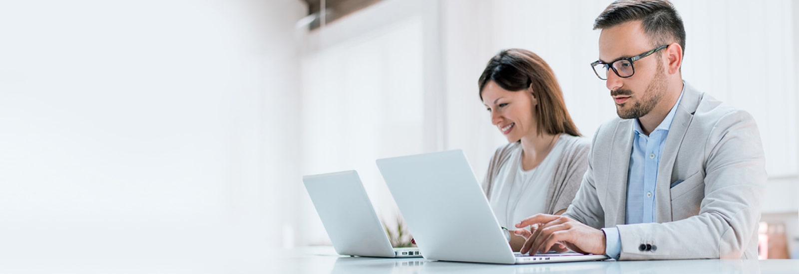 Two administrators are managing devices using LG SuperSign Control+ on personal PCs.