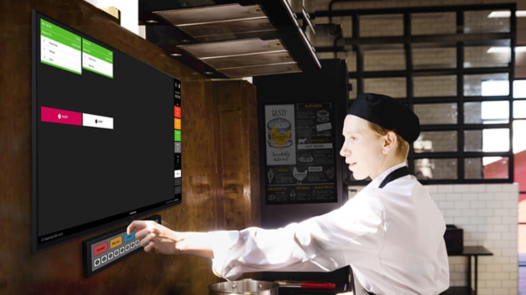 A kitchen staff member is checking order details on the kitchen display.