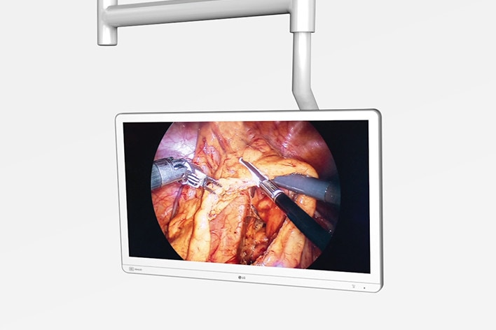 The image shows a 9.7 kg lightweight medical display mounted on a ceiling, displaying a surgical procedure.	