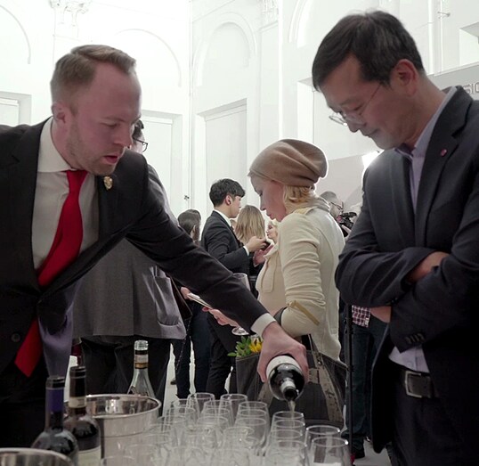 waiter is pouring drinks for a man at the lg signature artweek 2018 in russia