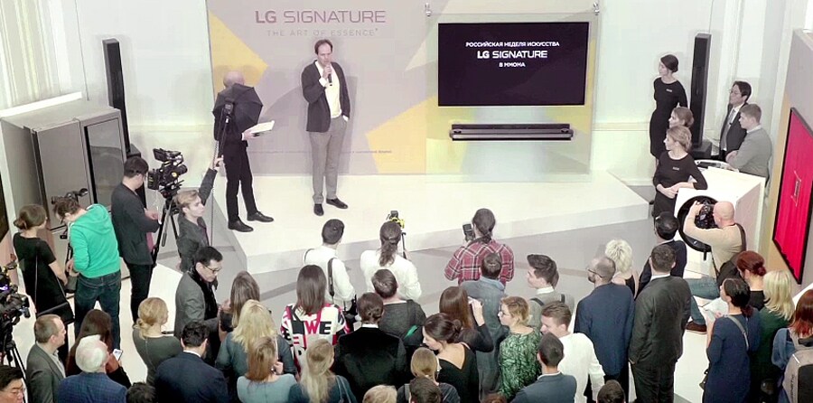 many people and reporters are staring the main stage on which presenter is introducing lg signature product at the lg signature artweek 2018 in russia