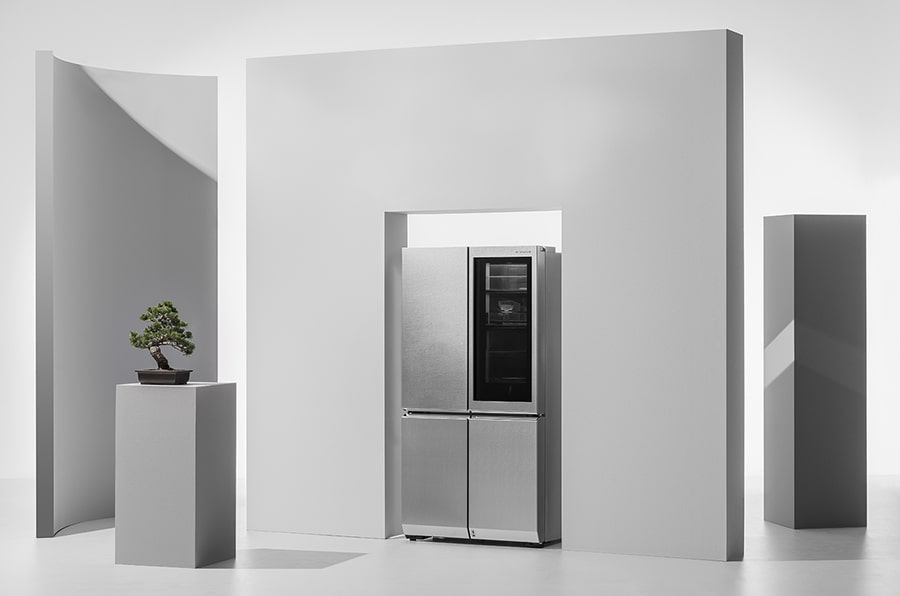 lg signature refrigerator is laid right under the wall that has square hole that fit into it with a japanese plant pot next to it