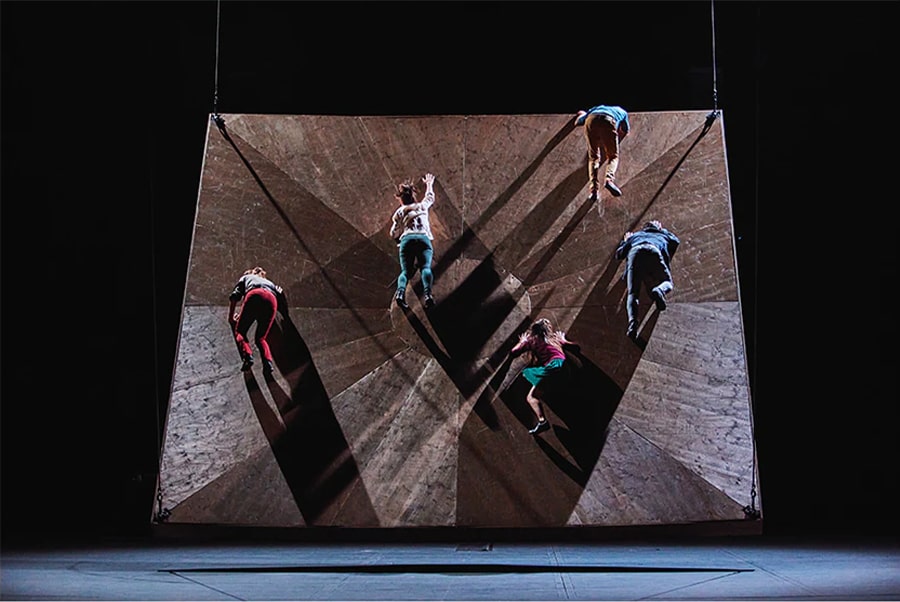 A photo of male and female dancers appearing to fall from an uneven surface.