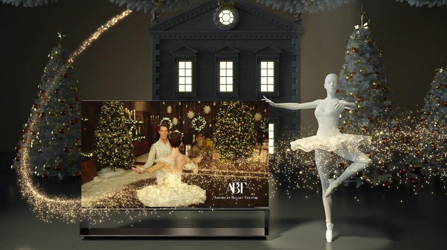 LG SIGNATURE Rollable OLED TV R positioned alongside Christmas trees and a statue of a ballerina displays ABT's holiday performance of The Nutcracker onscreen.