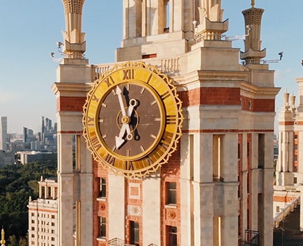 A closeup of a clock on an ornate tower.
