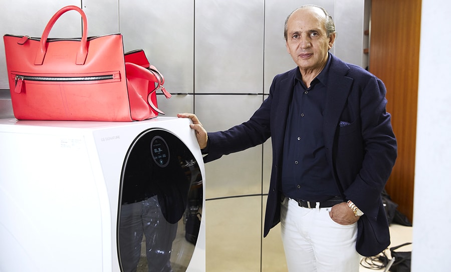 hadi teherani is standing right next to the lg signature washing machine on which one red bag is laid