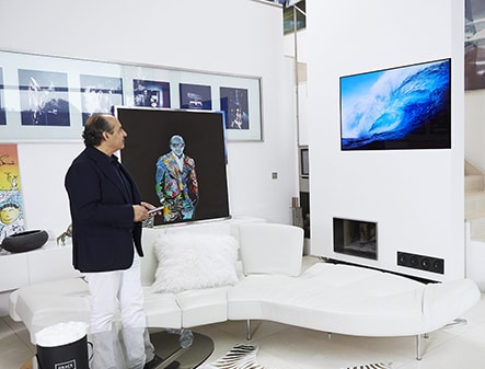 hadi teherani is staring lg signature oled tv which is hung on the wall in his house