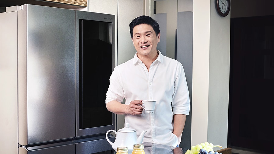 leslie tay is standing in the kitchen with lg signature refrigerator back of him