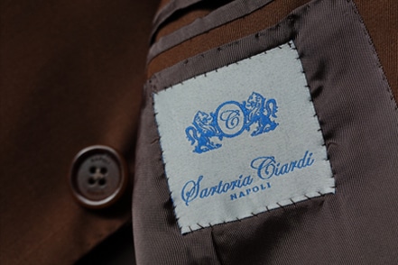 A tag on sewn on the lining of a suit that reads 'Santoria Ciardi.'