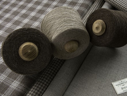 Brown and tan spools of thread rest atop tan fabric.