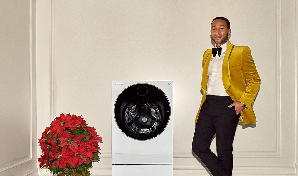 John Legend smiling and standing beside a washer