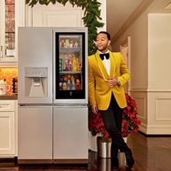 John Legend leaning slightly on a refrigerator with a see-through door