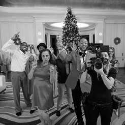John Legend and crew, including a cameraperson holding a large camera, posing for a photo