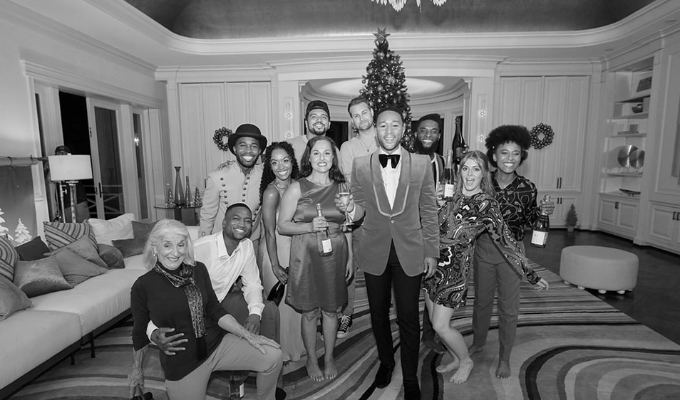 John Legend and crew posing for a photo in front of a Christmas tree