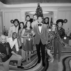 John Legend and crew posing for a photo in front of a Christmas tree