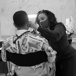 John Legend sitting in a makeup chair while a makeup artist works on him