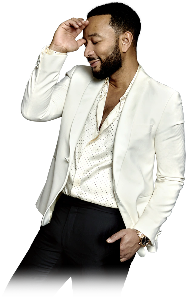 John Legend in a white shirt and jacket, smiling with one hand at his forehead and one in his pocket