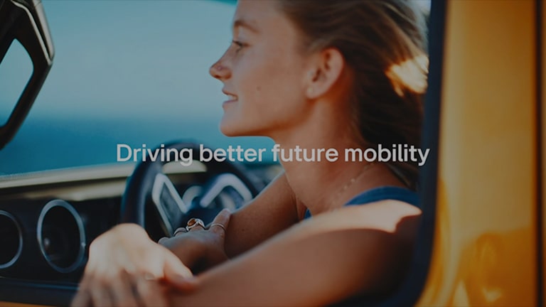 A woman in a yellow car, white text written as driving better future mobility'.