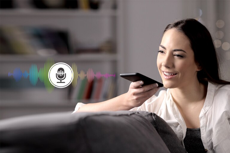 Μια γυναίκα χειρίζεται την τηλεόραση μιλώντας σε ένα τηλεχειριστήριο που διαθέτει αναγνώριση φωνής.