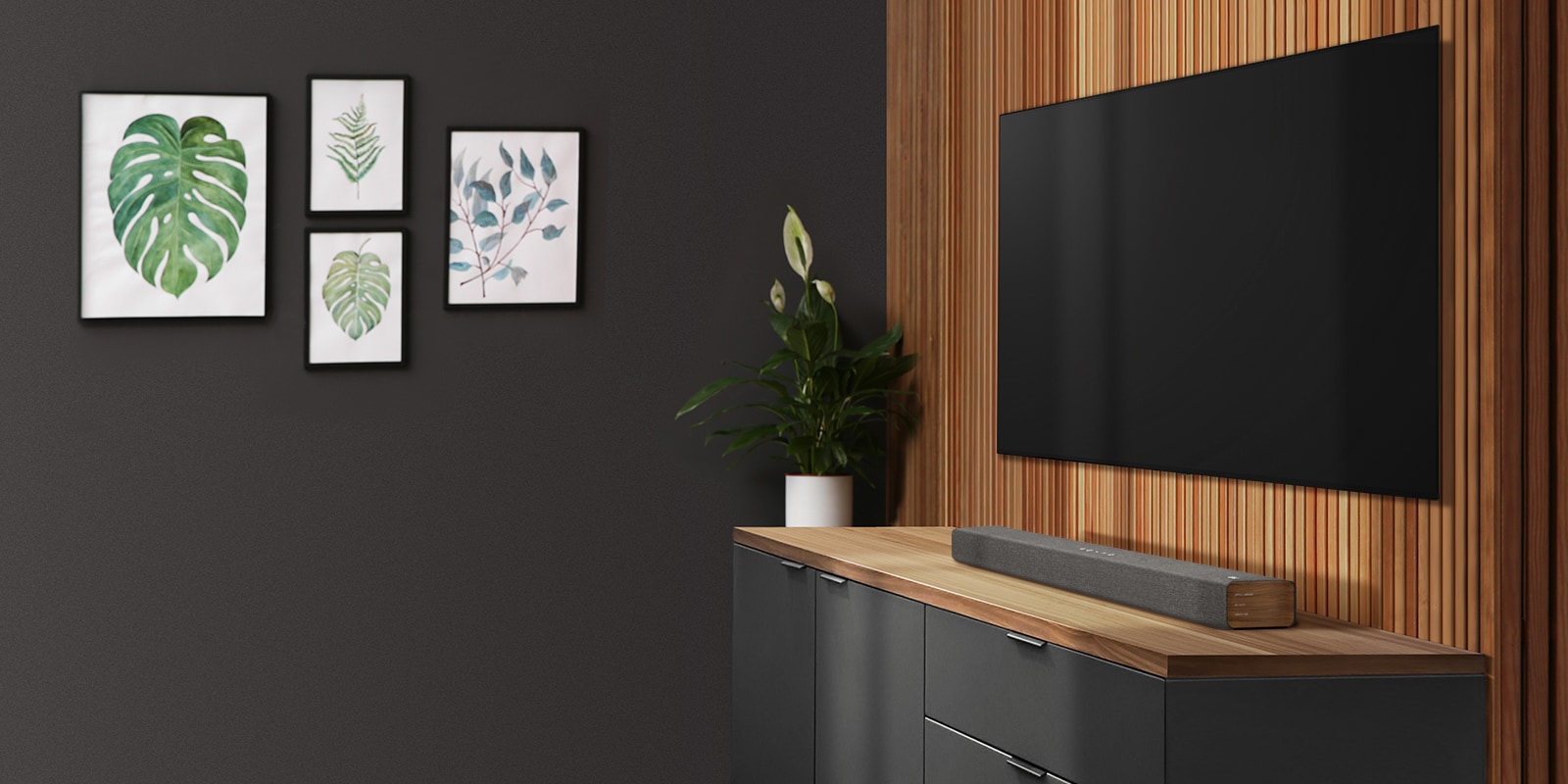 Ένα soundbar και μια τηλεόραση τοποθετημένα σε έναν τοίχο με ξύλινη επένδυση. Στον σκούρο τοίχο είναι αναρτημένα τέσσερα κάδρα με εικόνες.
