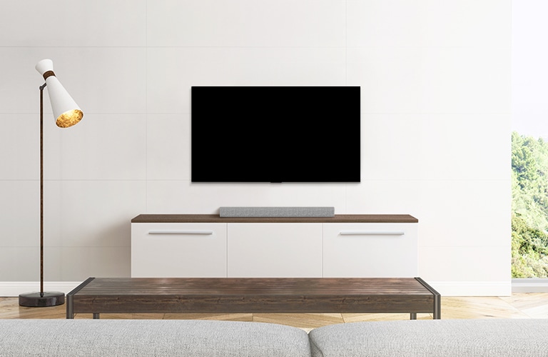 Μια τηλεόραση και ένα soundbar τοποθετημένα σε ένα λιτό σαλόνι.