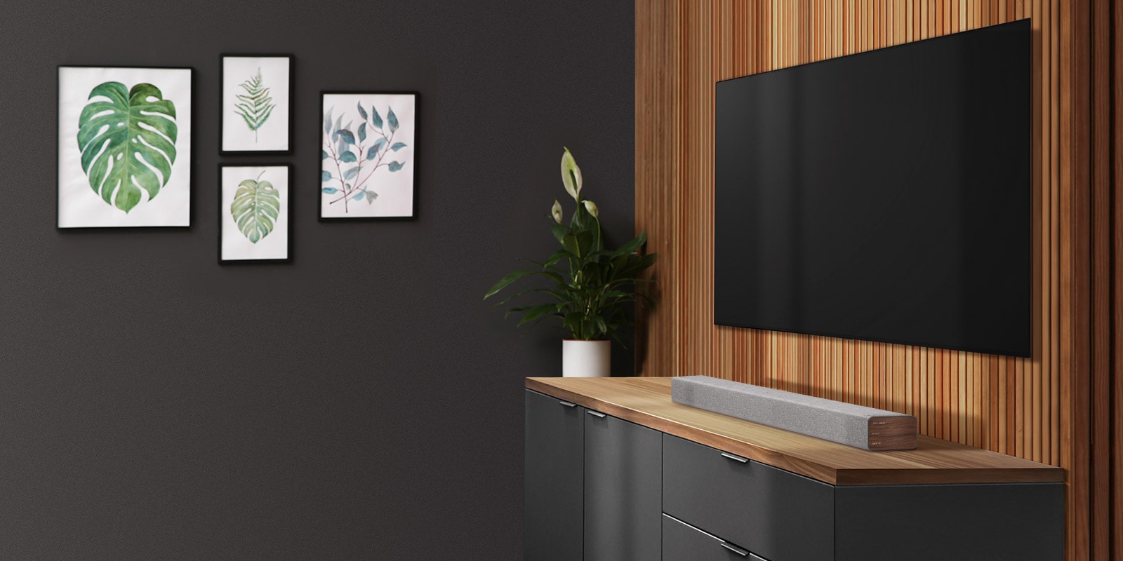 Ένα soundbar και μια τηλεόραση τοποθετημένα σε έναν τοίχο με ξύλινη επένδυση. Στον σκούρο τοίχο είναι αναρτημένα τέσσερα κάδρα με εικόνες.