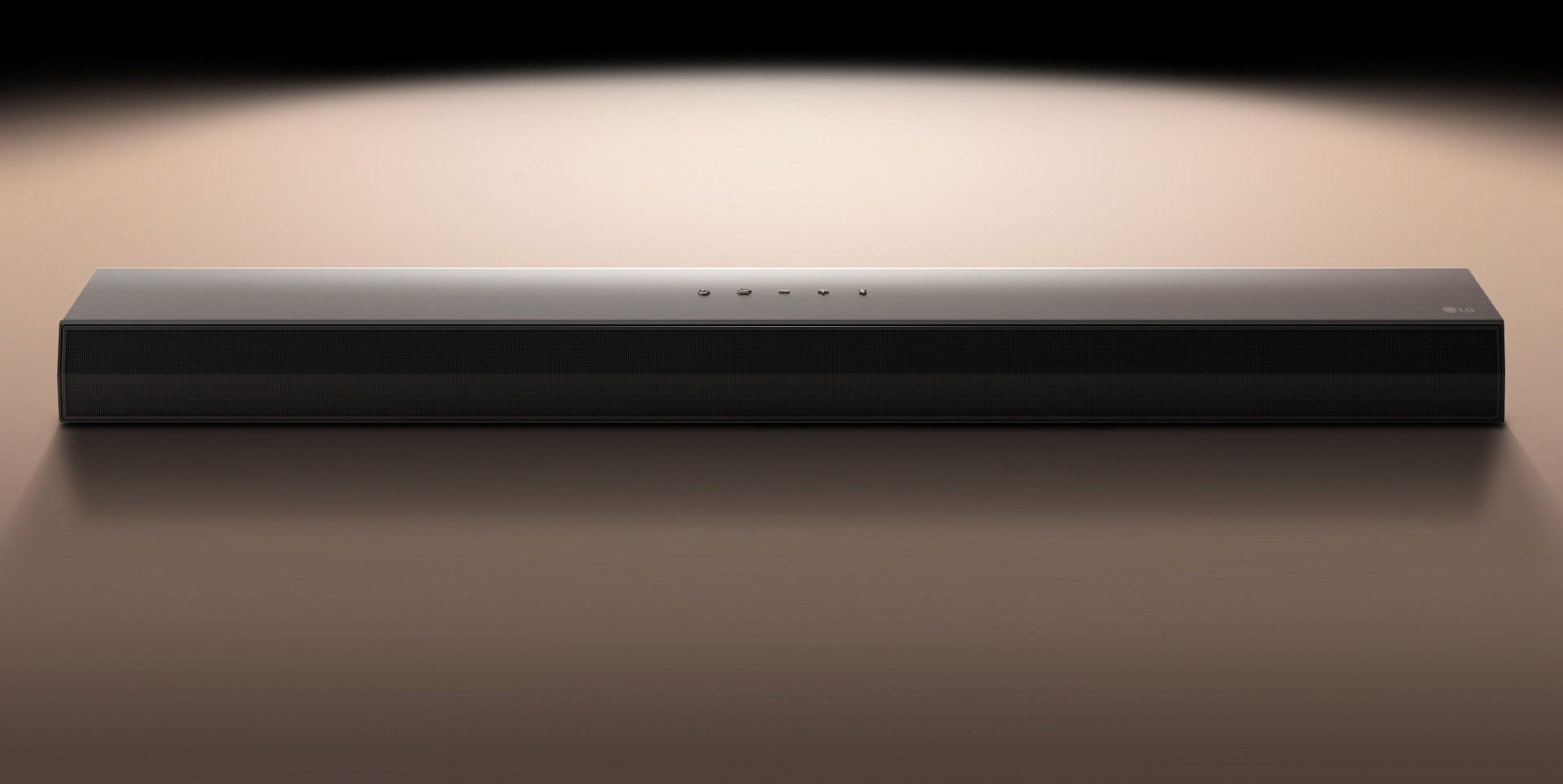 LG Soundbar μπροστά από μαύρο φόντο που φωτίζεται με προβολέα. 