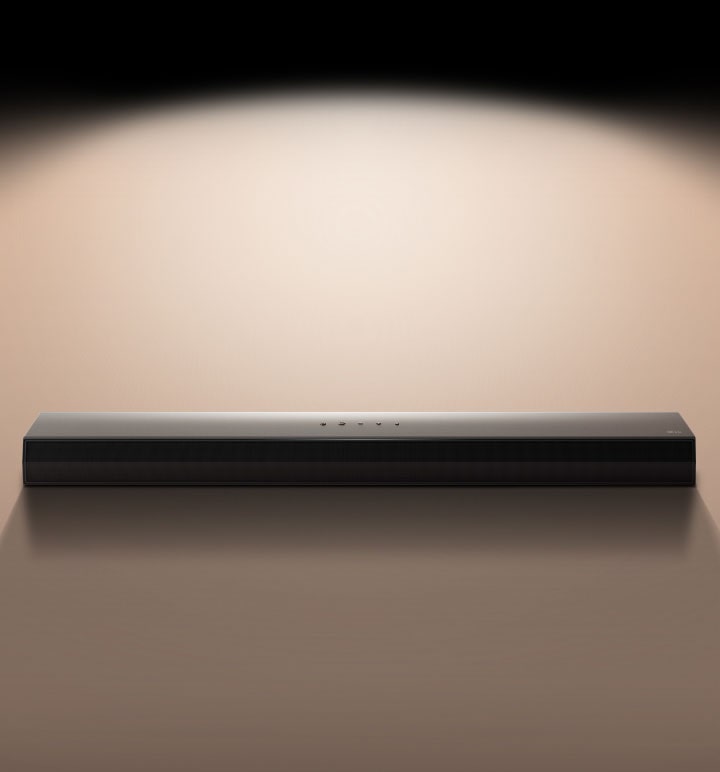 LG Soundbar μπροστά από μαύρο φόντο που φωτίζεται με προβολέα. 