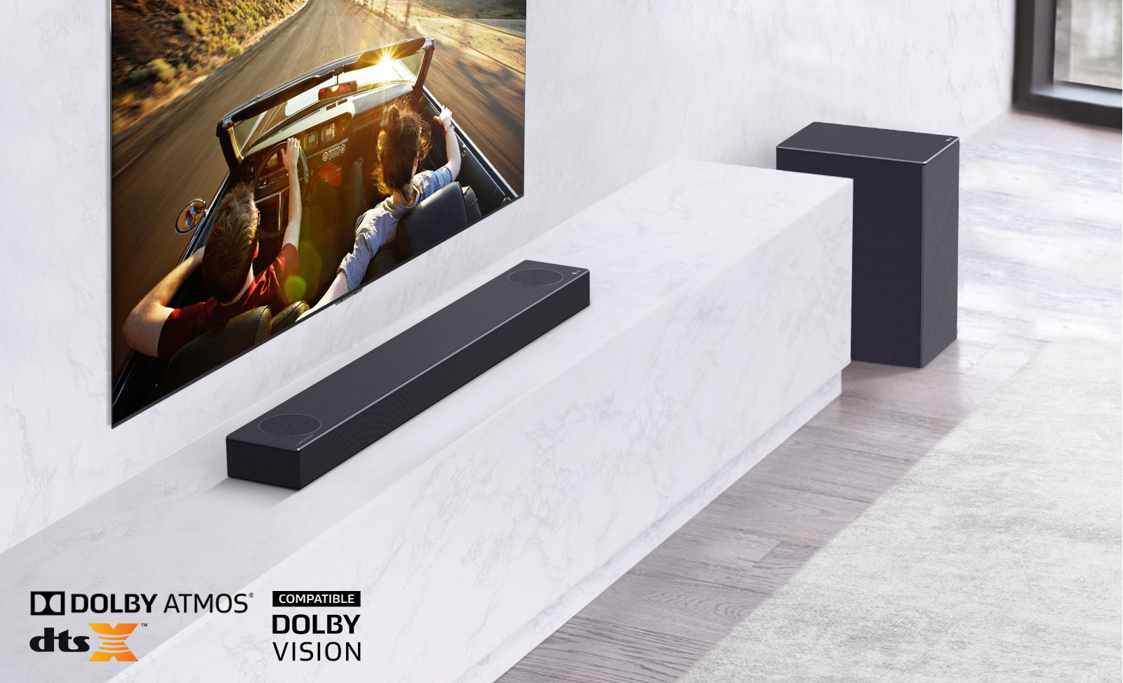 Μια τηλεόραση στον τοίχο και το LG Sound Bar σε ένα λευκό ράφι με Subwoofer. Στην τηλεόραση - ένα ζευγάρι σε αυτοκίνητο.