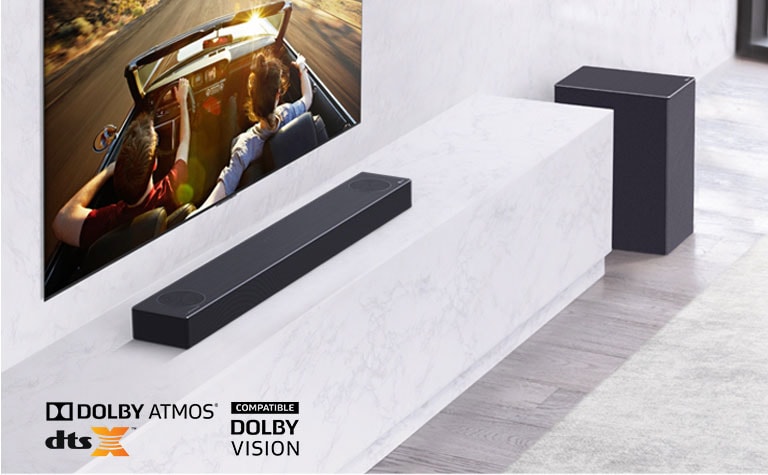 Μια τηλεόραση στον τοίχο και το LG Sound Bar σε ένα λευκό ράφι με Subwoofer. Στην τηλεόραση - ένα ζευγάρι σε αυτοκίνητο.
