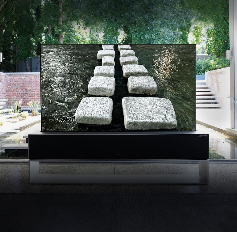 Αναδιπλούμενη τηλεόραση, που βρίσκεται μπροστά από τη λίμνη ενός πολυτελούς σπιτιού, που δείχνει ένα πλακόστρωτο (κάντε κύλιση προς τα κάτω στη σελίδα)