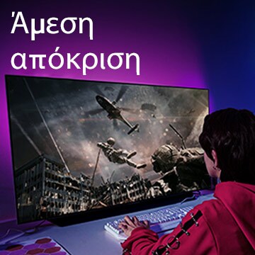 Ένα κορίτσι που παίζει ένα παιχνίδι σε υπολογιστή. Στην μεγάλη οθόνη της τηλεόρασης φαίνεται ένας στρατιώτης που κατεβαίνει από ένα ελικόπτερο.