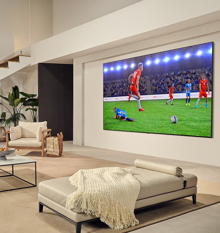 Μια οικογένεια στο σαλόνι. Έχουν μια LG TV επιτοίχιας τοποθέτησης με μια εξαιρετικά μεγάλη οθόνη, η οποία καλύπτει σχεδόν ολόκληρο τον τοίχο. Παρακολουθούν έναν συναρπαστικό αγώνα ποδοσφαίρου στη μεγάλη και καθηλωτική οθόνη.