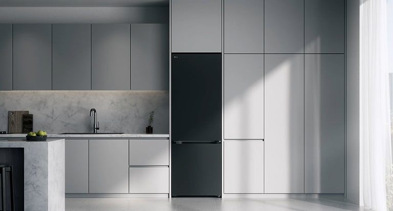 LG ψυγειοκαταψύκτης, εντοιχισμένος σε γκρι ντουλάπια δίπλα σε πάγκο με μαρμάρινη επιφάνεια και εστία επαγωγής, με μεγάλο παράθυρο στα δεξιά.