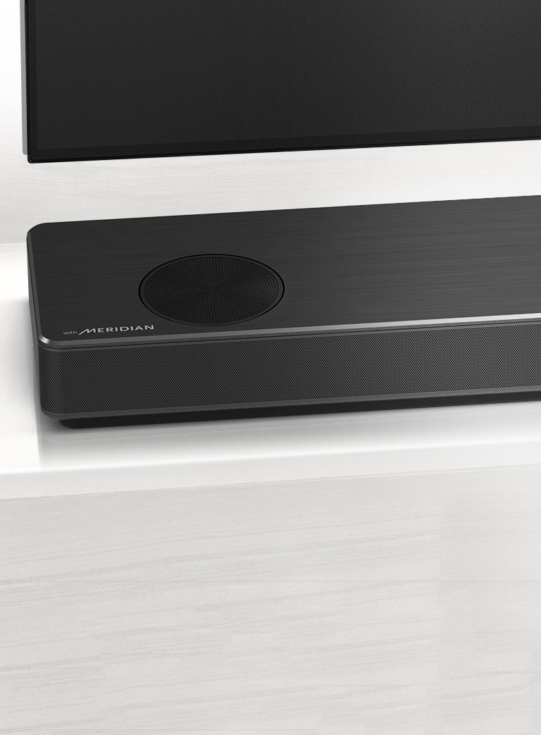Κοντινό του LG Sound Bar με το λογότυπο της Meridian κάτω αριστερά. Η κάτω αριστερή πλευρά της τηλεόρασης είναι επίσης ορατή.