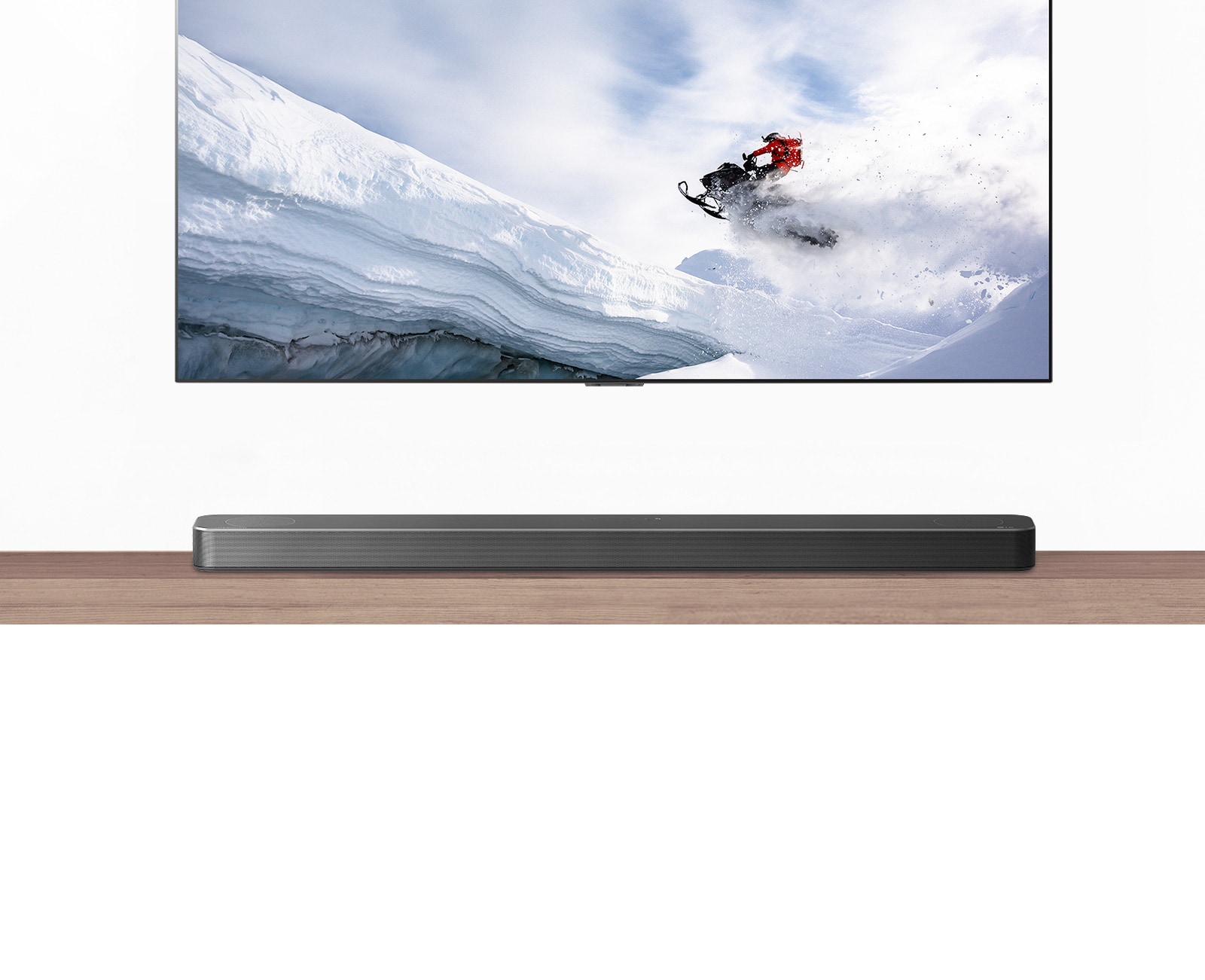 TV και SoundBar. Η TV δείχνει έναν άντρα σε snowmobile σε βουνά. Το λογότυπο του HDMI 2.1 κάτω από την τηλεόραση.
