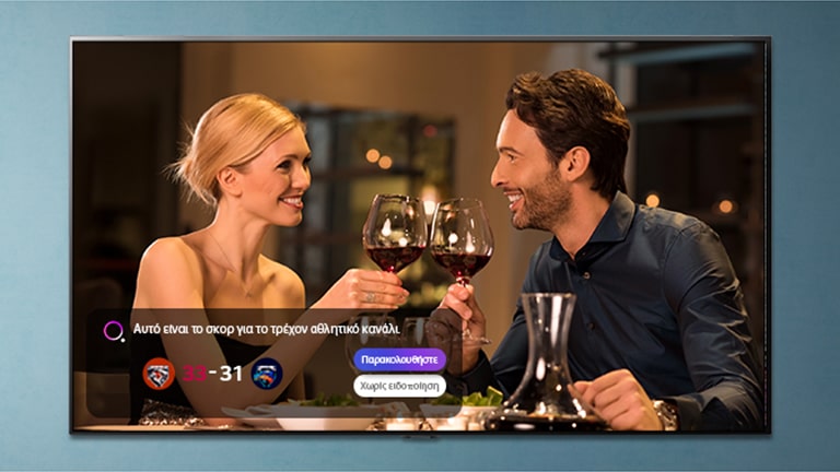 Μια οθόνη τηλεόρασης που απεικονίζει έναν άνδρα και μια γυναίκα που τσουγκρίζουν τα ποτήρια τους, ενώ εμφανίζονται αθλητικές ειδοποιήσεις