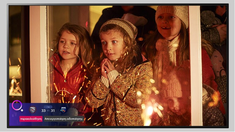 Οθόνη τηλεόρασης που δείχνει μια σκηνή από μια Χριστουγεννιάτικη ταινία με μια αθλητική ειδοποίηση