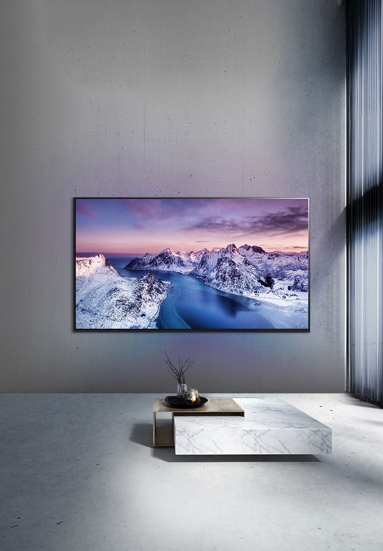 Μια τηλεόραση UHD στερεωμένη στον τοίχο πίσω από ένα τραπεζάκι με διαρρύθμιση σε στυλ zen.