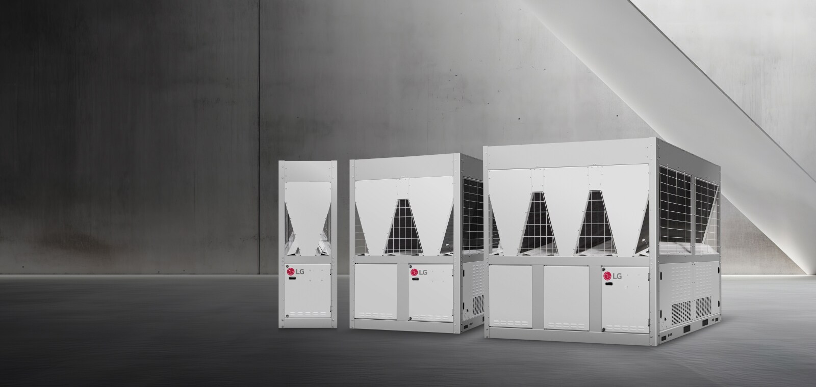Τρία LG inverter scroll chiller εμφανίζονται σε έναν χώρο με μινιμαλιστικούς τσιμεντένιους τοίχους και απαλό φωτισμό. 