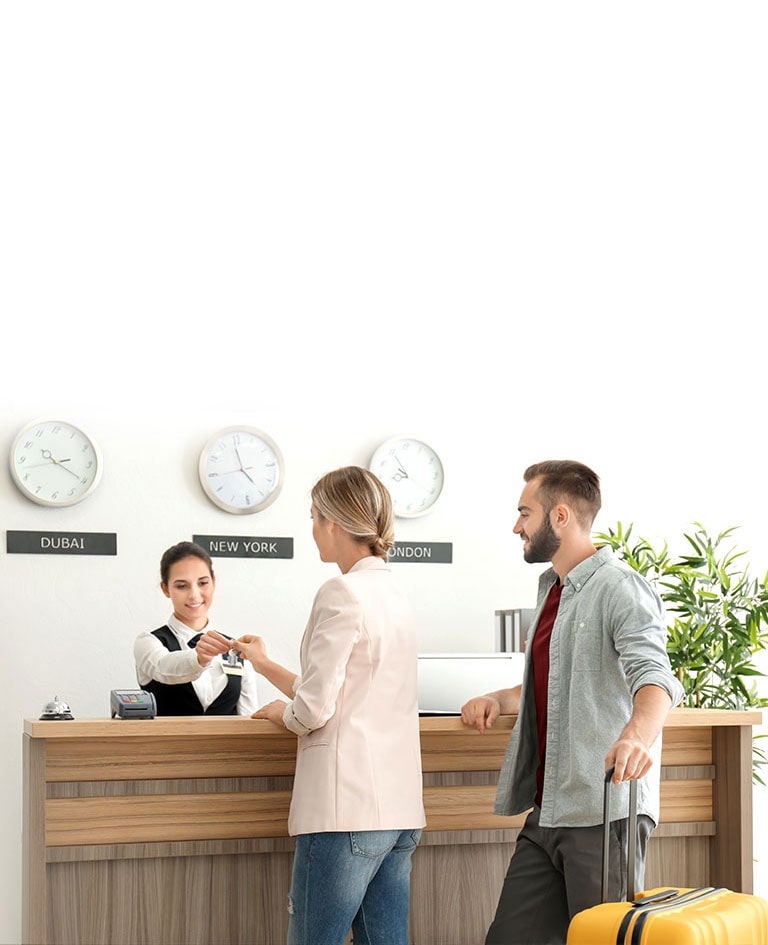Μια εικόνα ενός ζευγαριού που κάνει check-in με έναν ρεσεψιονίστ στο λόμπι του ξενοδοχείου.