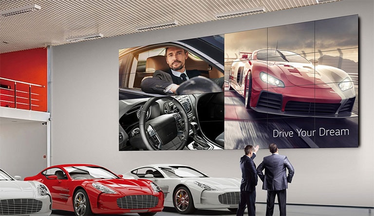 Ένα μεγάλο video wall είναι εγκατεστημένο στον τοίχο μιας έκθεσης αυτοκινήτων και στην οθόνη φαίνεται μια διαφήμιση αυτοκινήτου.