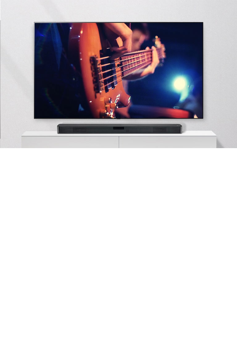 Μια τηλεόραση στον τοίχο με το Sound Bar σε ένα λευκό ράφι. Η τηλεόραση δείχνει έναν άνδρα να παίζει κιθάρα.