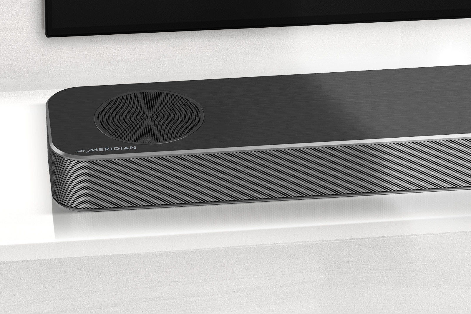 Κοντινό πλάνο της αριστερής πλευράς του LG Soundbar με το λογότυπο της Meridian στην κάτω αριστερή γωνία. Η κάτω αριστερή πλευρά της τηλεόρασης είναι επίσης ορατή.