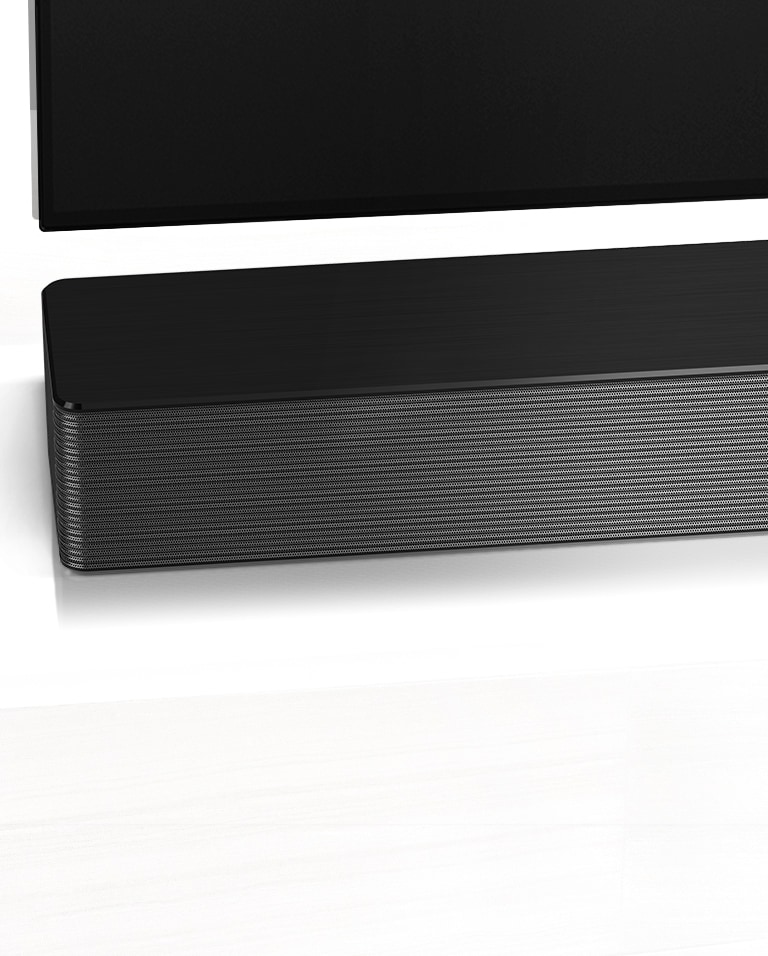 Κοντινό πλάνο του LG Soundbar στην αριστερή του γωνία. Η κάτω αριστερή πλευρά της τηλεόρασης είναι επίσης ορατή.