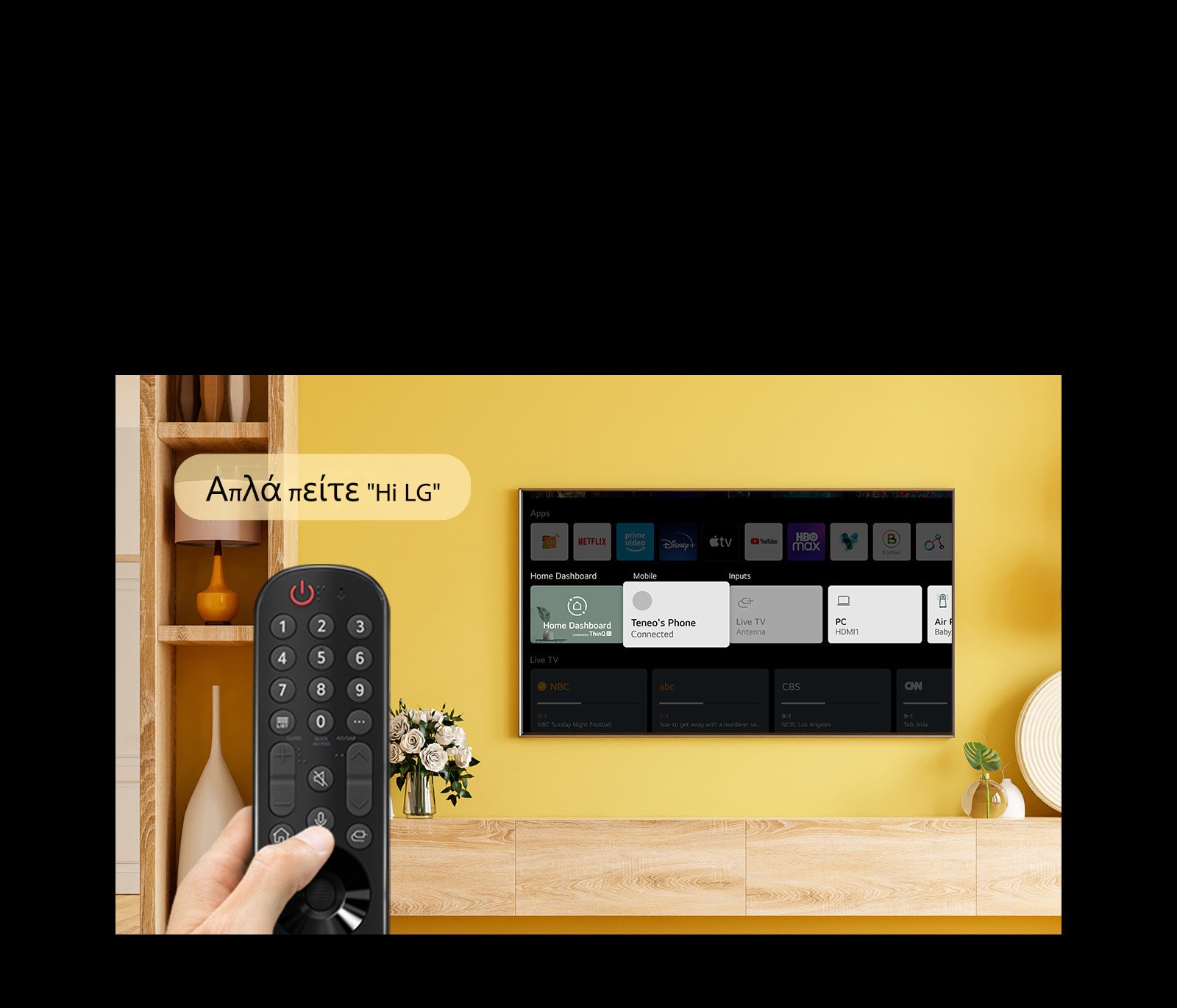 Κάποιος κρατάει ένα τηλεχειριστήριο τηλεόρασης μπροστά από την οθόνη της τηλεόρασης. Ένα συννεφάκι κειμένου λέει "Just say Hi LG".